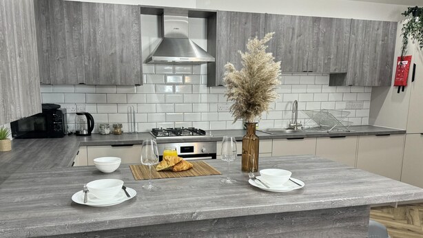 Een moderne keuken met een centraal eiland, witte kasten en een roestvrijstalen afzuigkap.