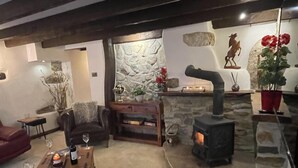 Una sala de estar acogedora con chimenea de piedra, un sofá de cuero cómodo y una mesa de centro de madera con una copa de vino.