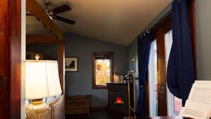 A cozy room with a wooden floor, a fireplace, a ceiling fan, and a window with curtains. - Romantic Wine Country Retreat Spa-Hot Tub & Sauna (Burdett)