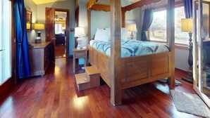 A four-poster bed with a wooden frame, a nightstand with a lamp, and a view of the outdoors through a window. - Romantic Wine Country Retreat Spa-Hot Tub & Sauna (Burdett)
