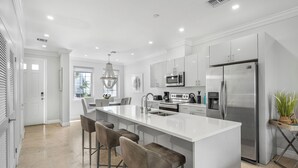 A modern kitchen with a large island, stainless steel appliances, and bar stools.
