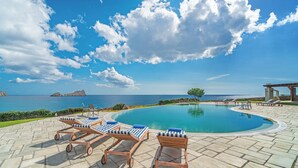 Ein Poolbereich mit Liegestühlen und Blick auf das Meer.