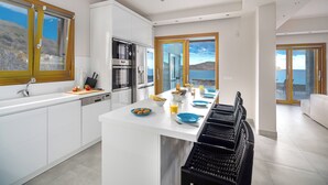 Eine moderne Küche mit weißen Schränken, einem eingebauten Backofen und einem Essbereich mit einem langen Tisch.