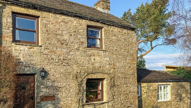 A stone building with two windows, a door, and a small window with a view of the sky. - 1 Swallowholm Cottages (Arkengarthdale)