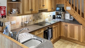 A kitchen with wooden cabinets, a stainless steel sink, a kettle, and a toaster. - 1 Swallowholm Cottages (Arkengarthdale)