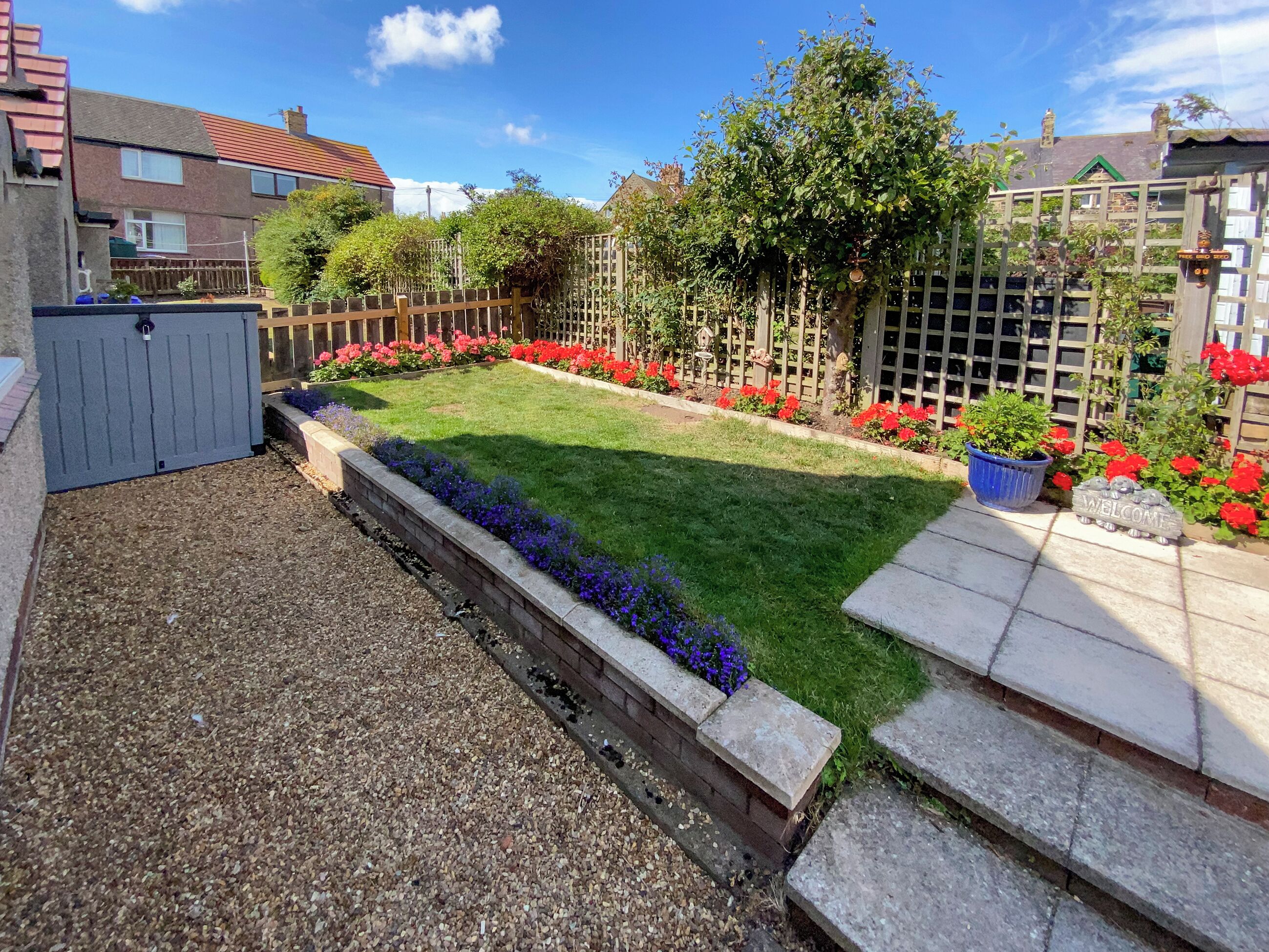 A well-maintained garden with a lawn, flower beds, and a wooden fence.