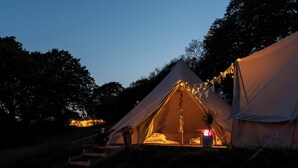 A large tent with a bed inside, surrounded by a staircase and potted plants. - Hapus Hideaway Retreat Site, Sleeps 29 (Abergele)