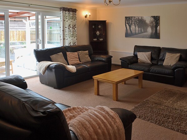 A living room with two black leather sofas, a wooden coffee table, and a patterned rug.