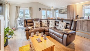 A modern living room with a brown leather sectional sofa, a wooden coffee table, and a dining area with a table and chairs.