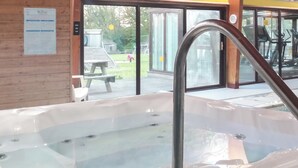 A hot tub with a metal faucet, a wooden bench, and a glass door leading outside. - 3 bedroom accommodation in Llanfynydd (Llanfynydd)