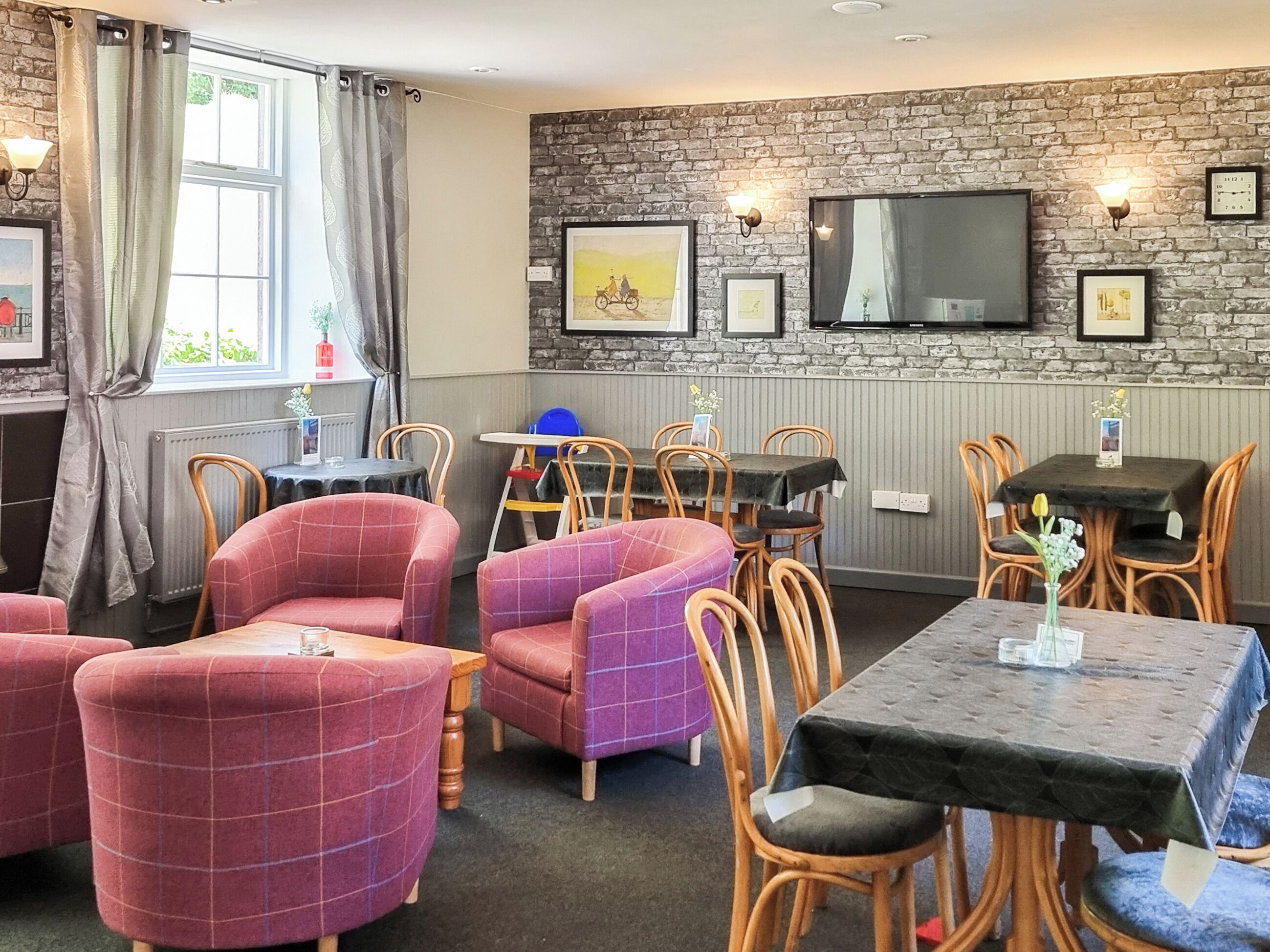 A cozy restaurant with brick walls, wooden chairs, and tables.