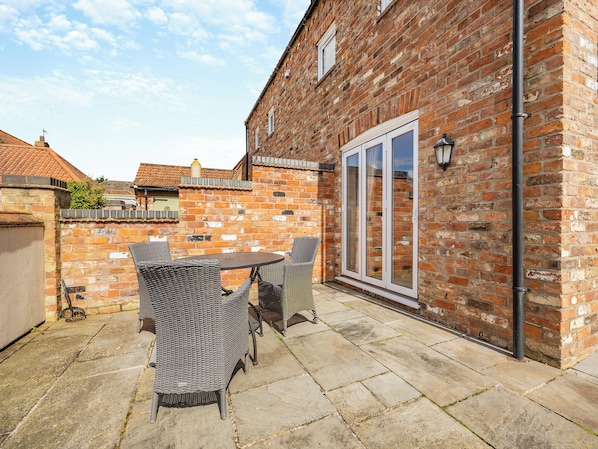 A patio with wicker furniture, a brick wall, and a sliding glass door.