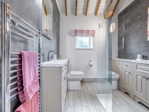 A modern bathroom with a glass shower enclosure, a white toilet, and a vanity with a mirror.