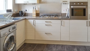 A modern kitchen with a built-in washer, stainless steel appliances, and light-colored cabinetry. - 3 bedroom accommodation in Beadnell (Beadnell)