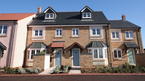 A two-story residential building with a brick facade, multiple windows, and a red-tiled roof. - 3 bedroom accommodation in Beadnell (Beadnell)