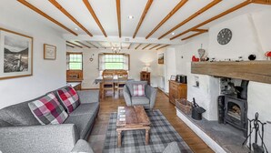 A cozy living room with a fireplace, a dining area, and a sofa with a plaid throw.