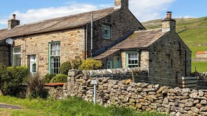 A stone building with a sloped roof, a chimney, and a 'No Parking' sign.