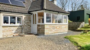 Een huis met een gevel van natuursteen, een kleine aangebouwd garage, en zonnepanelen op het dak.