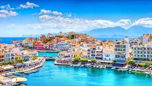 Un pueblo costero con edificios a lo largo de un muelle, barcos amarrados y un cielo azul despejado.