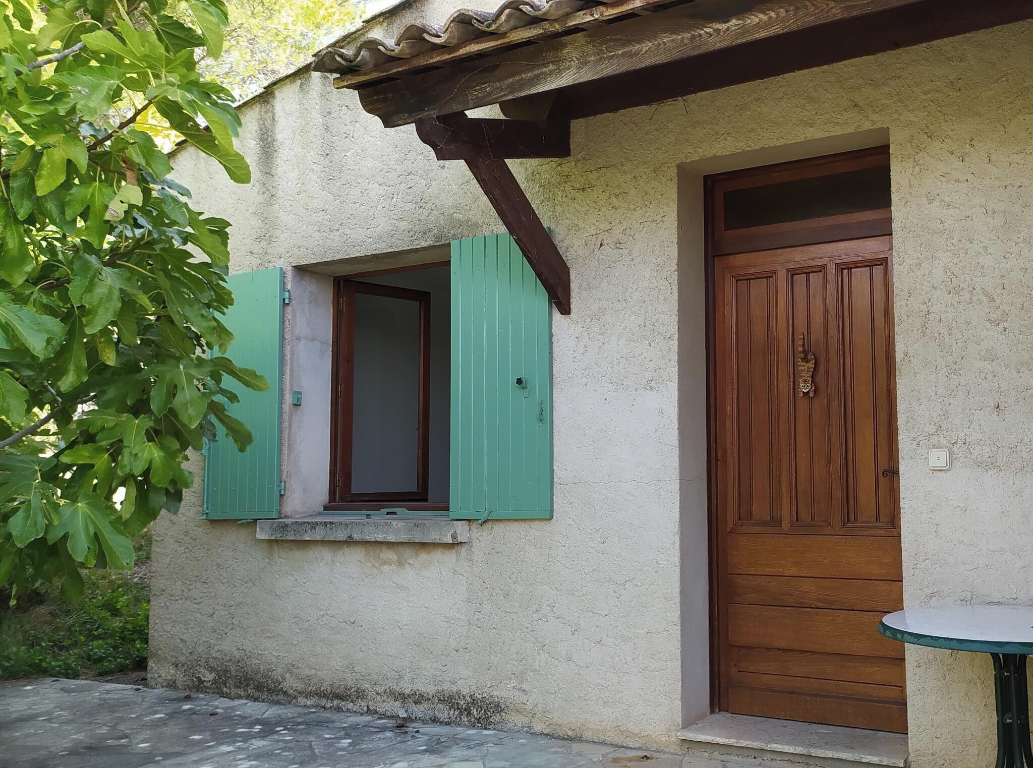 Un bâtiment rustique avec une porte en bois et une fenêtre dotée de volets verts.