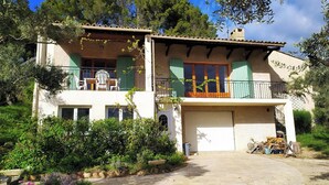 Una casa de dos pisos con balcón, garaje y jardín.