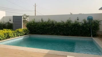 A rectangular swimming pool with a wooden deck in the foreground.