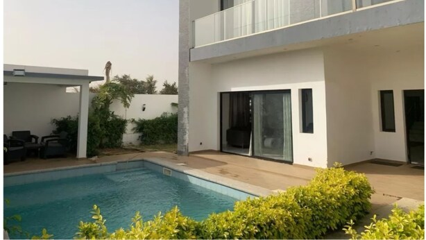 Una casa moderna a due piani con piscina, ampie finestre e un patio coperto.