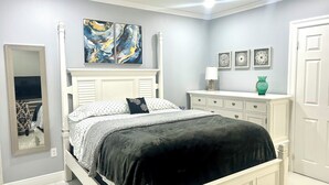 Ein Schlafzimmer mit einem weißen Bett, einem großen Spiegel und Bildern an der Wand.