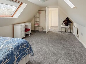 Une chambre à coucher comprenant un lit, un bureau, une chaise, un radiateur et une lucarne.