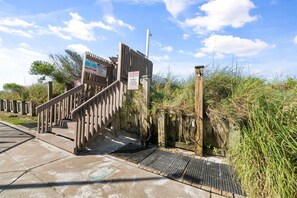 A wooden staircase leading to a gated entrance with informational signs.