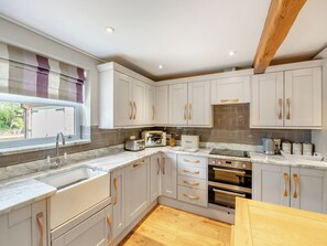 A modern kitchen with white cabinets, a built-in oven, a toaster, and a window with a view.
