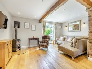 Una sala de estar con chimenea, muebles de madera, un sofá y un televisor.