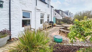 A white house with a stone pathway, wooden furniture, and potted plants. - A perfect location for a family island break by the seaside. (Lochranza)