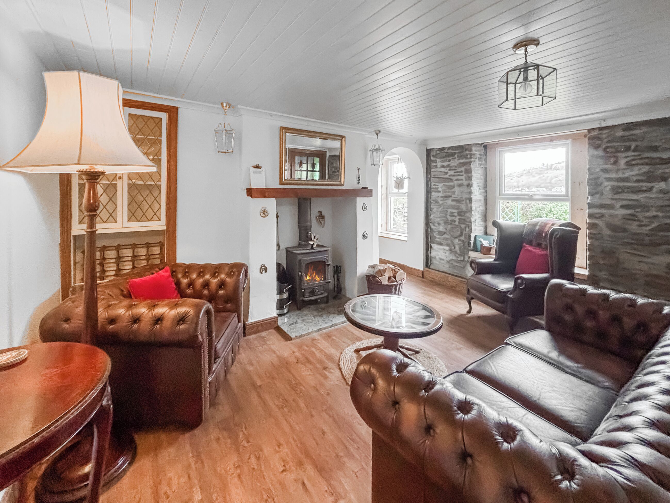 A cozy living room with leather sofas, a fireplace, and a stone wall.