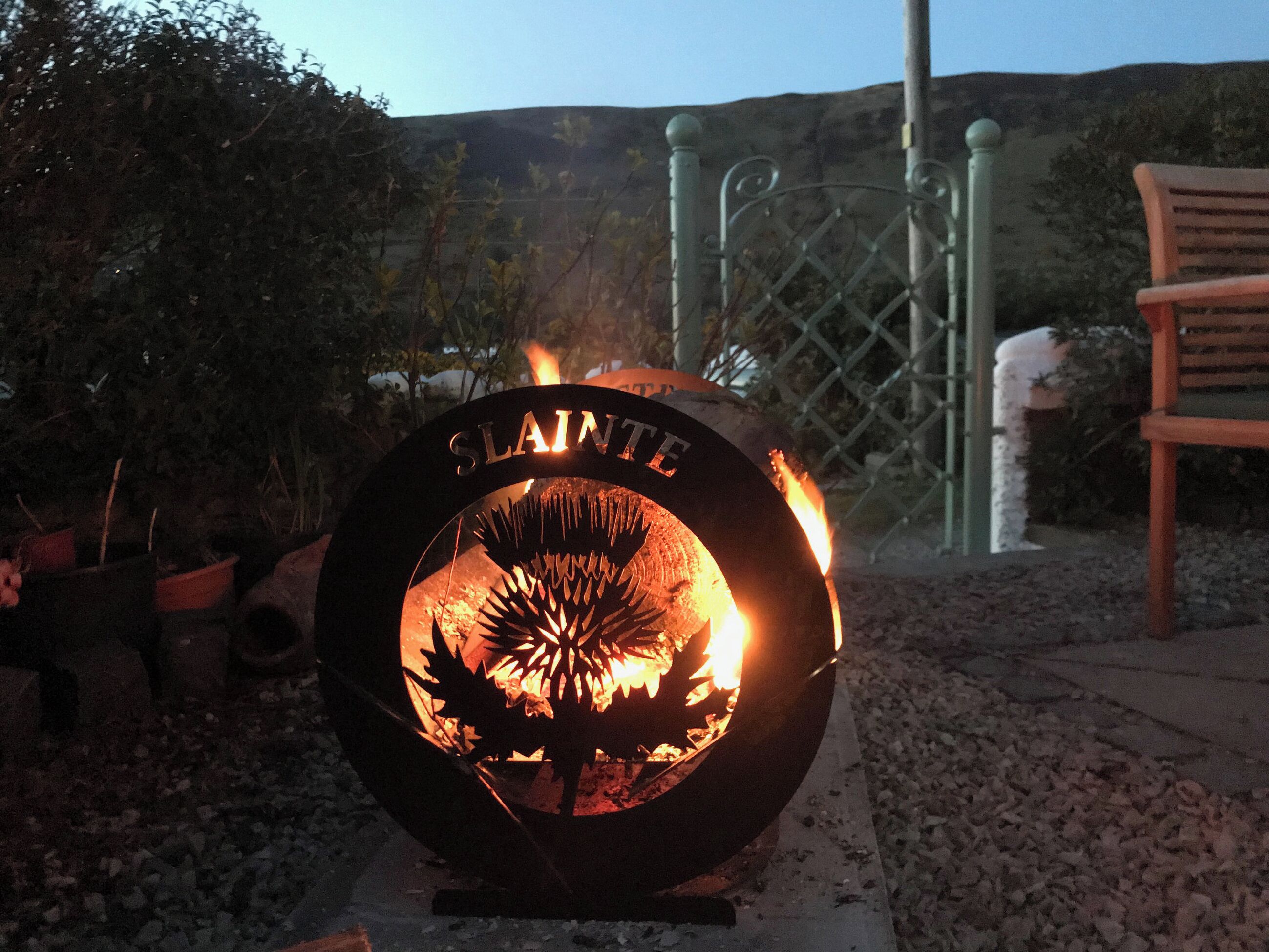 A metal fire pit with a decorative design and the word 'SLANTE' on it.