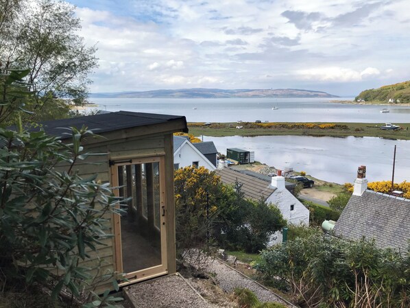 A coastal property with a wooden structure, a view of the sea, and a distant island.