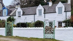 A white building with a traditional architectural style, featuring a symmetrical facade with multiple windows and a central door. - A perfect location for a family island break by the seaside. (Lochranza)