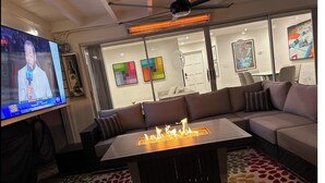 En moderne stue med et stort fladskærms-tv, en pejs, en sofa og en loftventilator.
