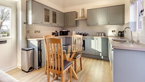 A modern kitchen with grey cabinets, a wooden dining table, and a stainless steel sink.