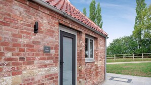 A brick building with a tiled roof, a door, and a window.