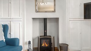 Een kamer met een open haard, een blauwe bank en een spiegel boven de open haard.