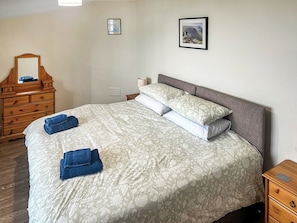 A neatly made bed with a floral bedspread, two pillows, and two folded towels. - Latrigg View - UK45177 (Threlkeld, near Keswick)