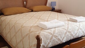 Ein Schlafzimmer mit einem hölzernen Bett, einem Nachttisch, einer Lampe und einem Sonnenuntergangsbild.
