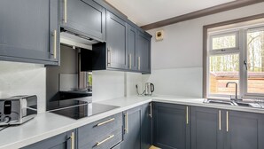 A modern kitchen with dark cabinets, a white countertop, a built-in oven, and a window with a view. - A peaceful location for a relaxing break with excellent fishing to enjoy. (Marston)