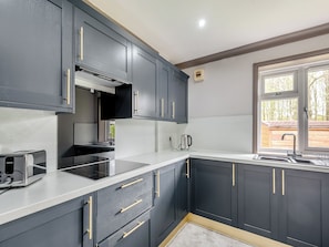 A modern kitchen with dark cabinets, a white countertop, a built-in oven, and a window with a view. - A peaceful location for a relaxing break with excellent fishing to enjoy. (Marston)