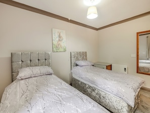 A bedroom with two beds, a bedside table, a mirror, and a painting on the wall. - A peaceful location for a relaxing break with excellent fishing to enjoy. (Marston)
