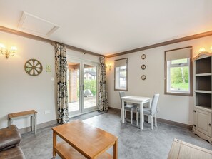 A room with a dining table, chairs, a sofa, a window with a view, and a wall-mounted clock. - A peaceful location for a relaxing break with excellent fishing to enjoy. (Marston)