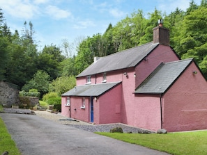A pink house with a stone wall, a blue door, and a paved driveway.