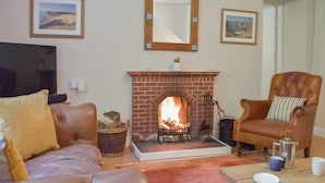 A living room with a fireplace, leather sofas, a coffee table, and a television.