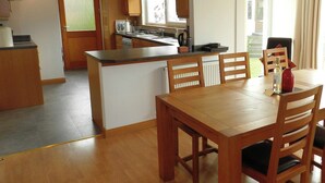 A modern kitchen with wooden cabinets, a central island, and a dining area with a table and chairs.